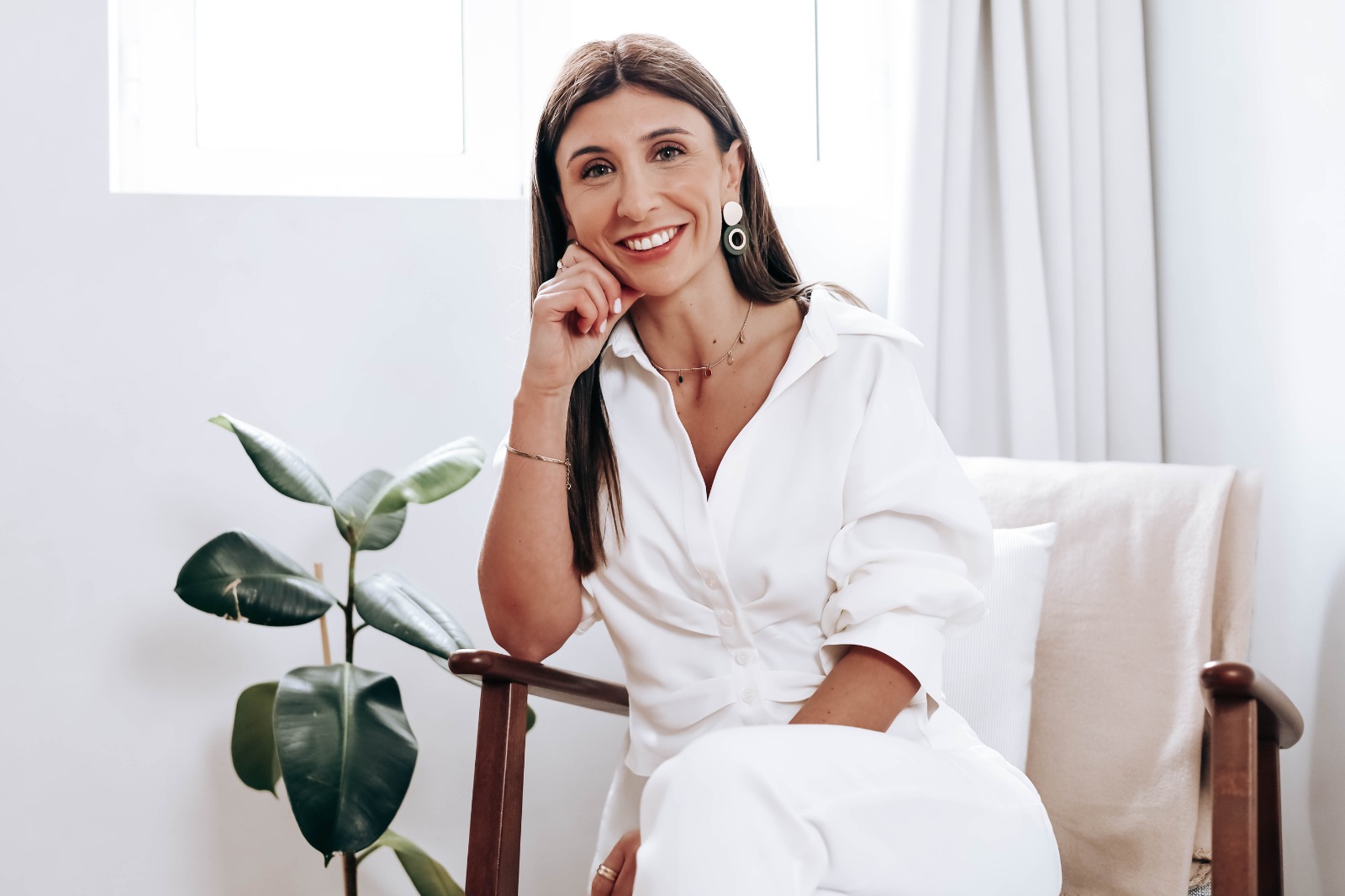 Flávia Santos sentada em ambiente tropical, com chávena e caderno