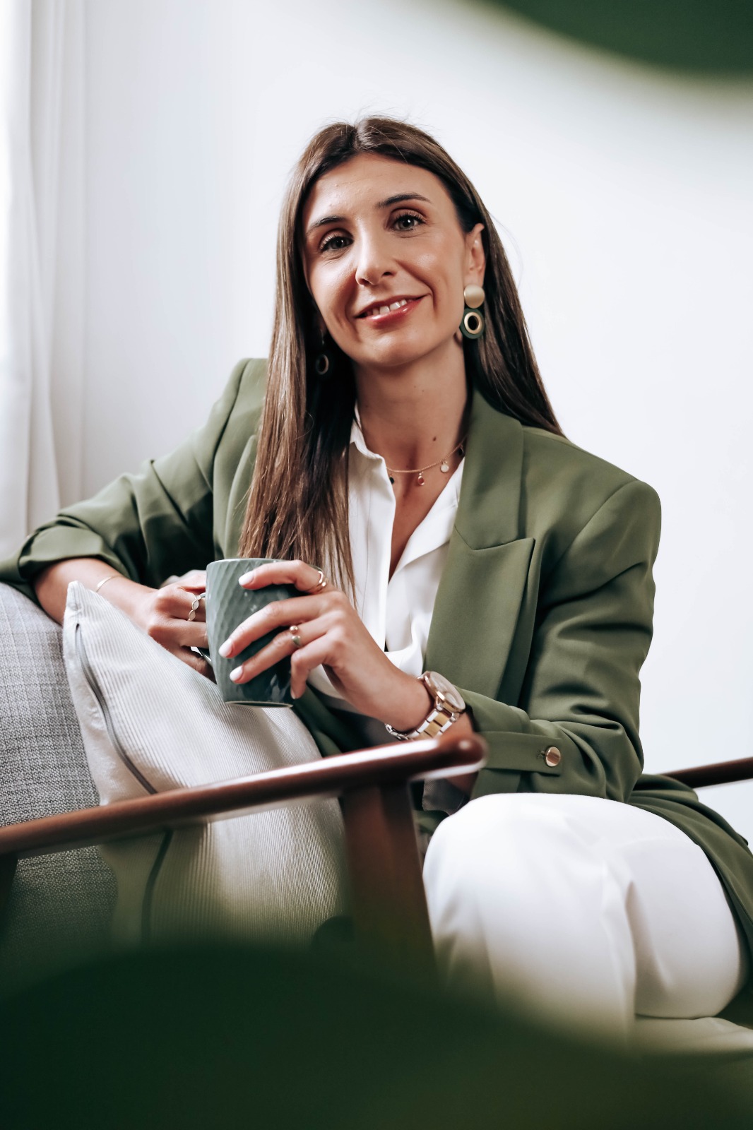 Flávia Santos, nutricionista e mentora, sentada num sofá com uma chávena